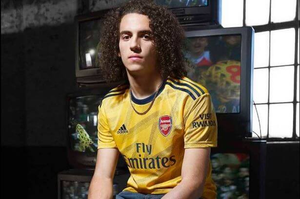 Seorang pria mengenakan jersey away kit Arsenal